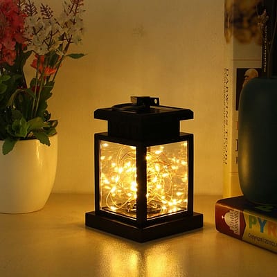 Farol LED solar modelo Vela y modelo Hada iluminando jardín de noche