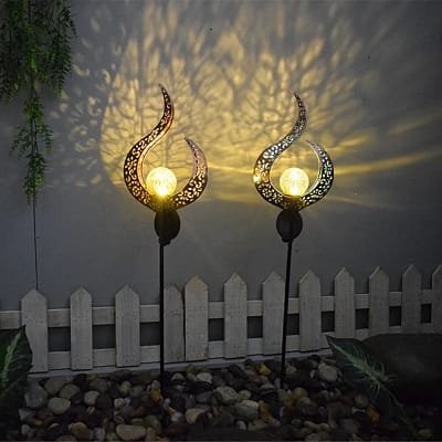 Estaca llama de cobre iluminando jardín con luz solar cálida