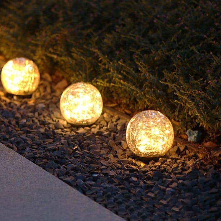 Estaca esfera craquelada solar iluminando sendero con luz cálida