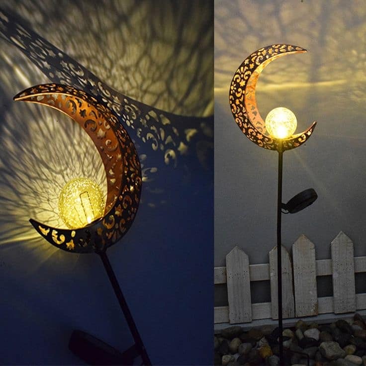 Estaca luna de cobre LED iluminando jardín con luz cálida